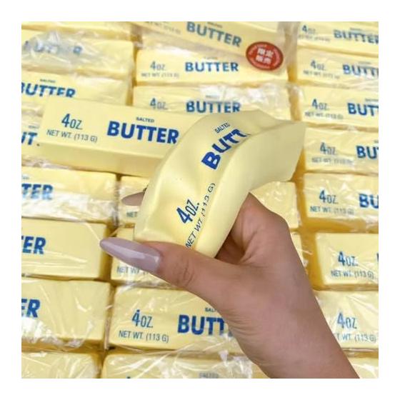 A hand bending a yellow butter stick squishy over a pile of stock